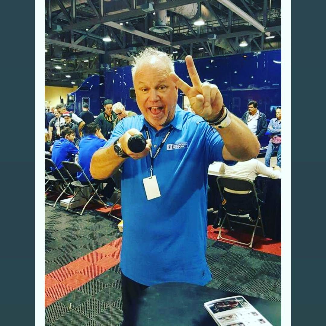 A man in a blue shirt is giving a peace sign