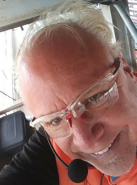 A man wearing glasses and a microphone is smiling.