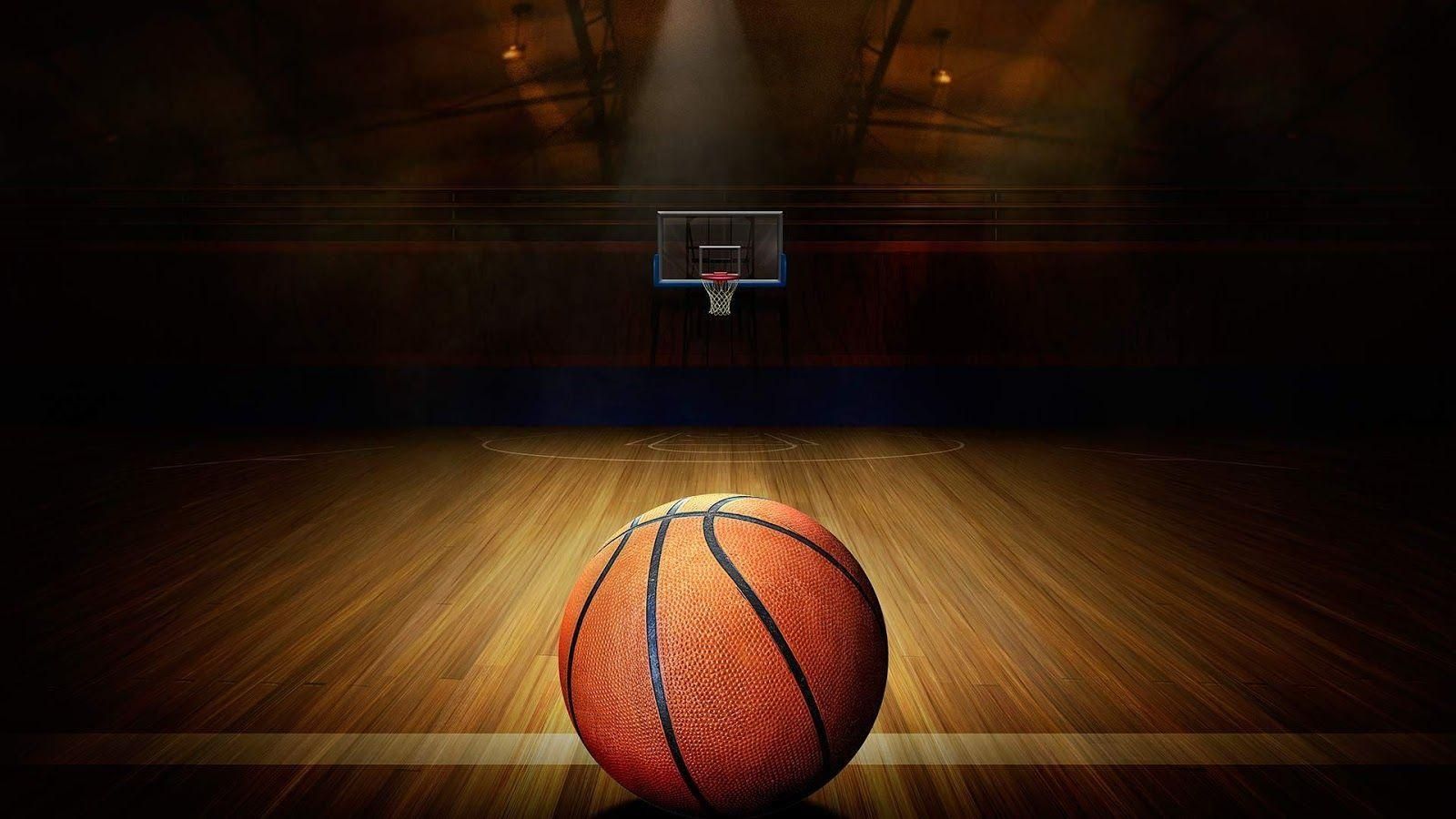 Basketball on a wooden court, lit spotlight on the hoop.