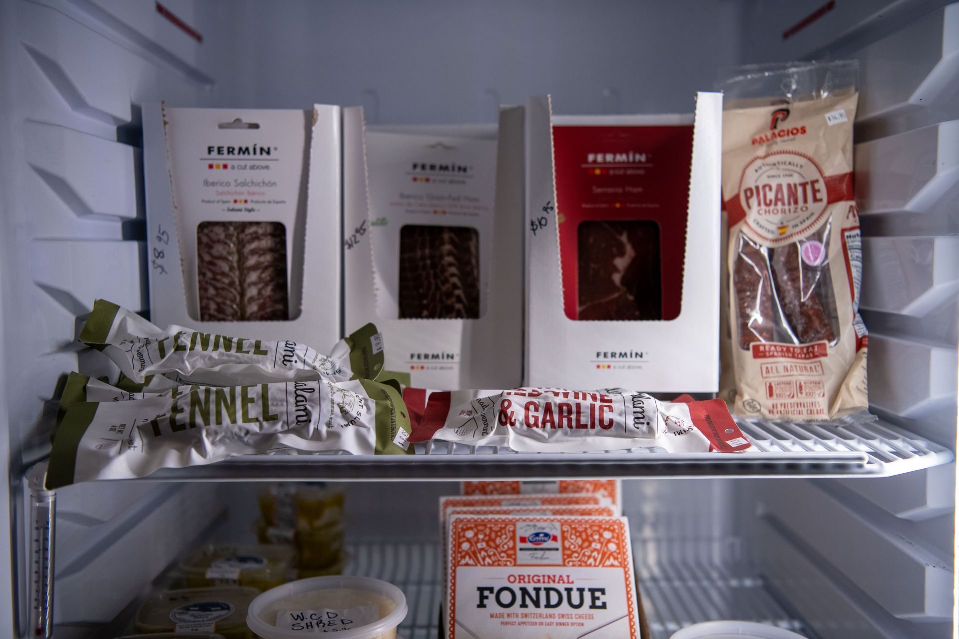 A refrigerator filled with a cured meats and a variety of food including fondue at Wine & Cheese Depot, Ludlow, VT