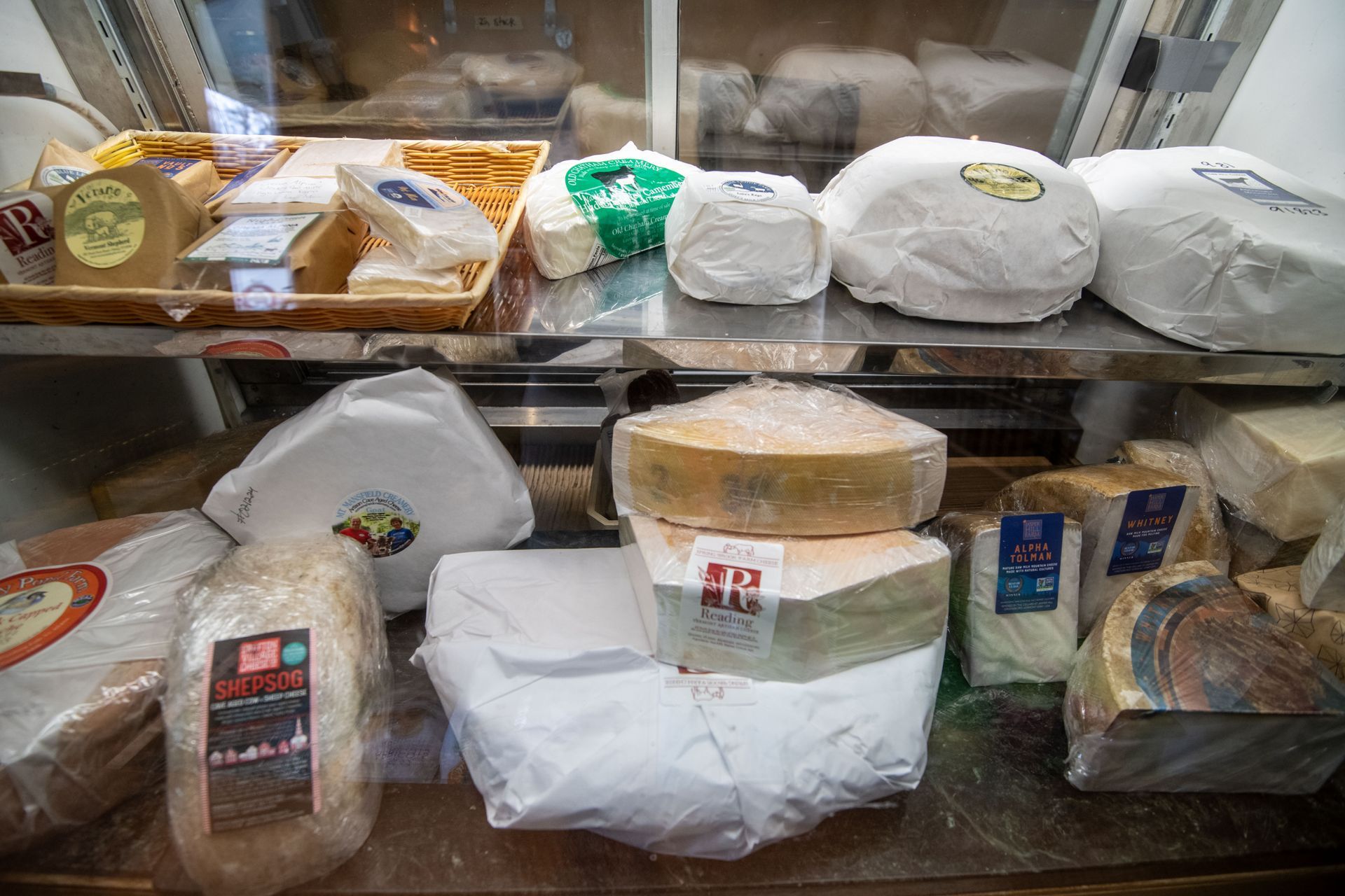 A display case filled with lots of different types of cheese in Ludlow, VT