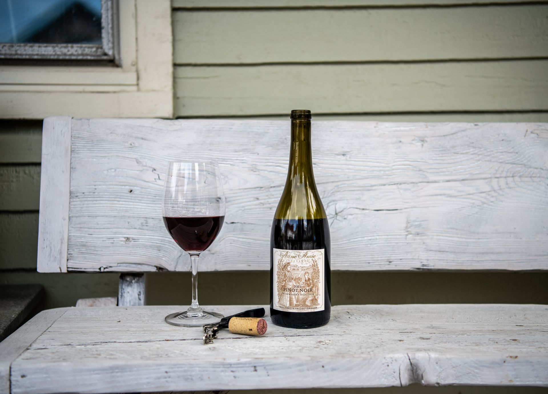A bottle of wine and a glass of wine are on a wooden table at Wine & Cheese Depot, Ludlow, VT