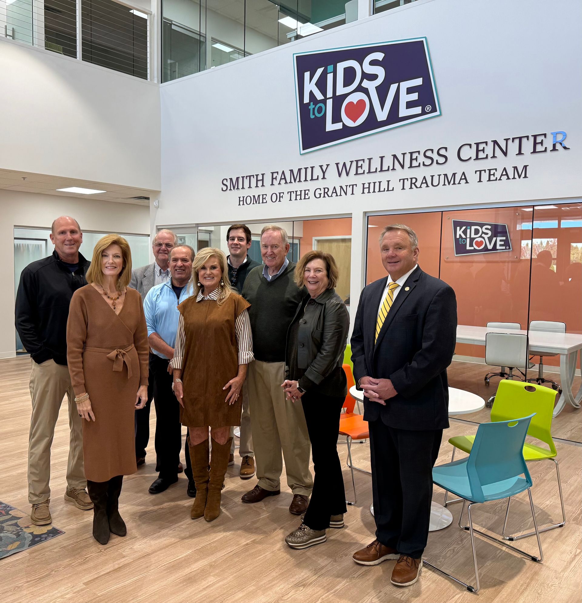 Group of people standing in a lobby with the "Kids to Love" logo on the wall.