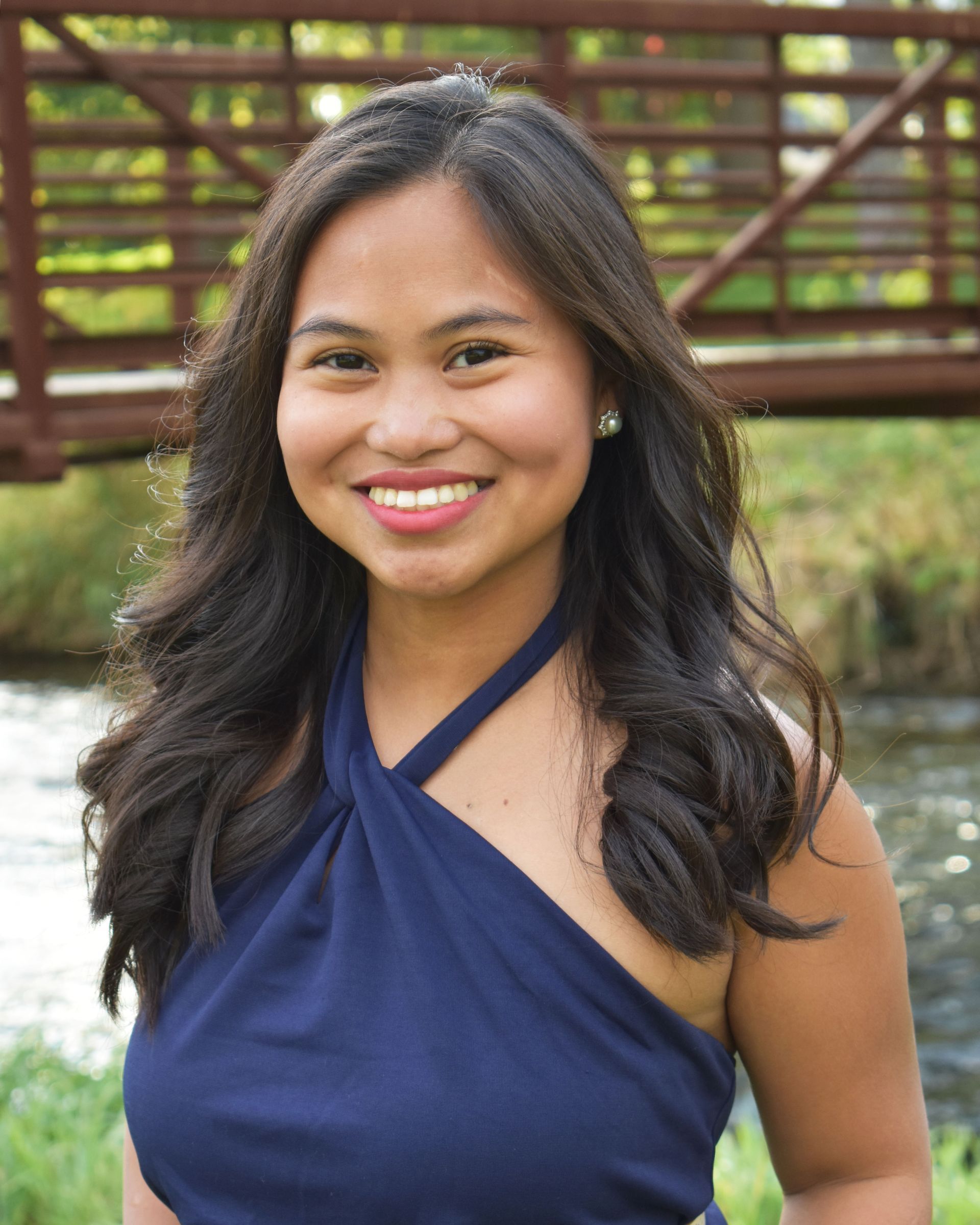 A woman wearing a white top and earrings is smiling for the camera.