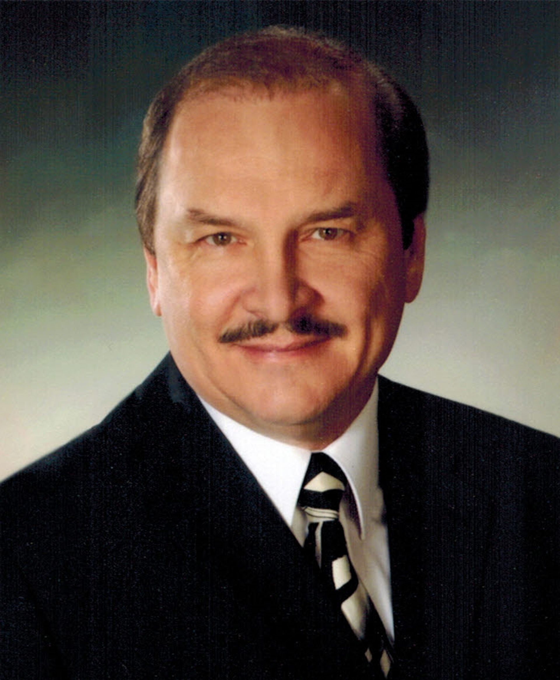 A man with a mustache is wearing a suit and tie