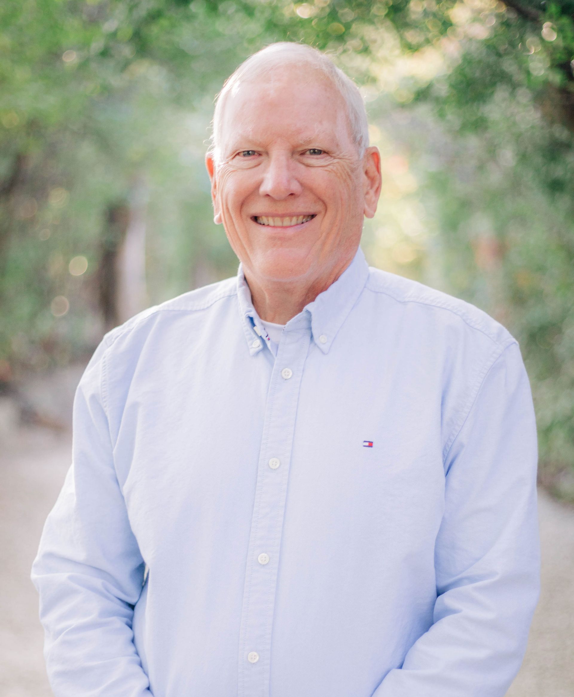 The man is wearing a blue shirt and smiling for the camera.