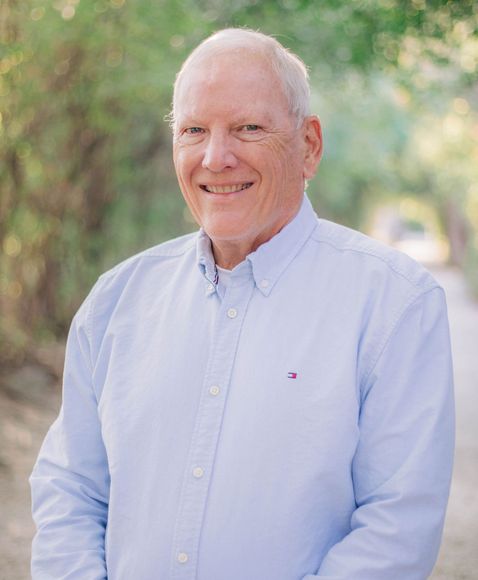 The man is wearing a blue shirt and smiling for the camera.