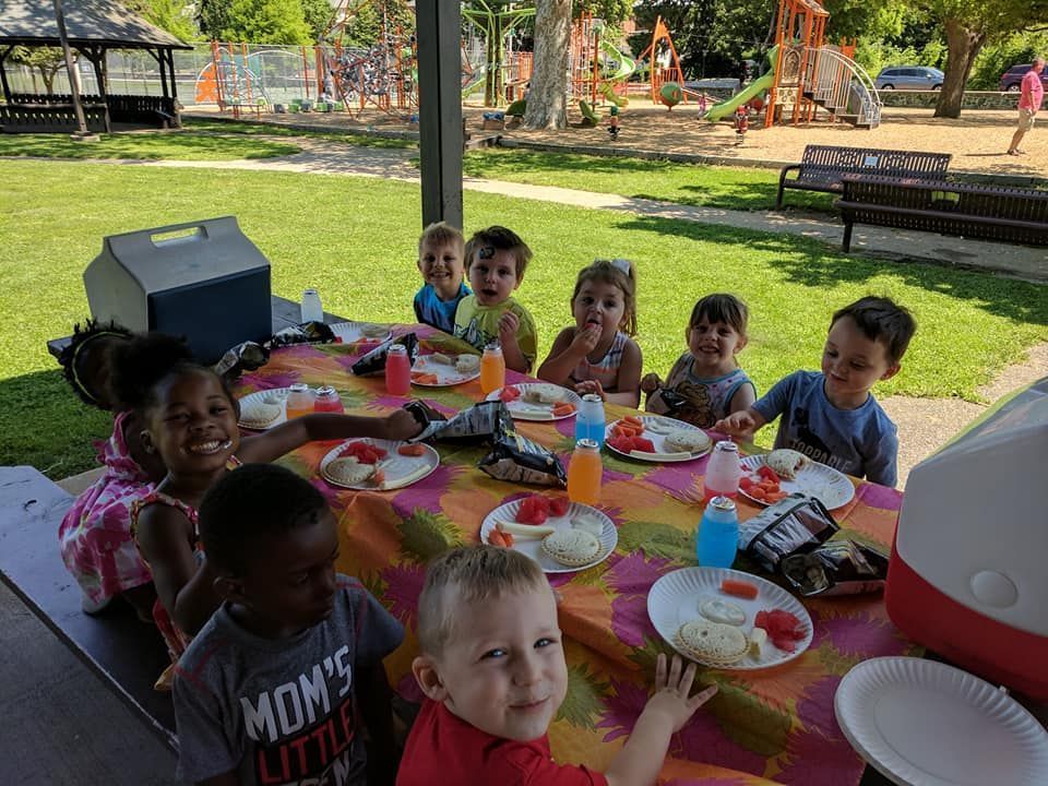 Children at a picnic table outdoors, smiling and eating watermelon. Children at a picnic table outdoors, smiling and eating watermelon.