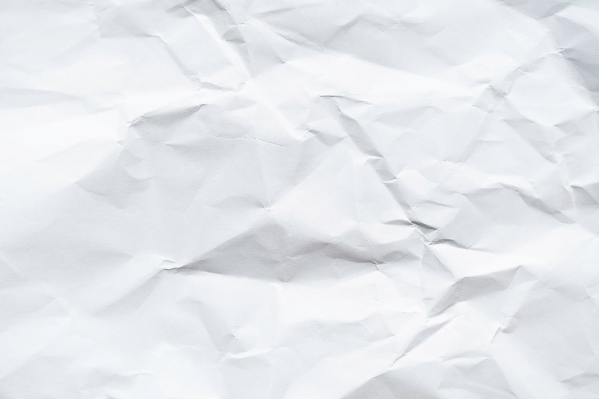 Crushed white paper, textured with folds and shadows.
