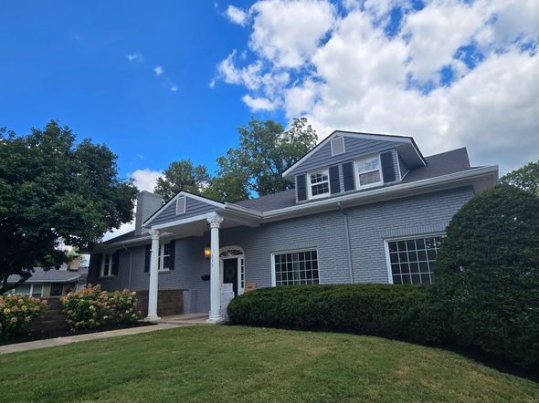 Blue house with white trim, porch with columns, under a blue sky with clouds.