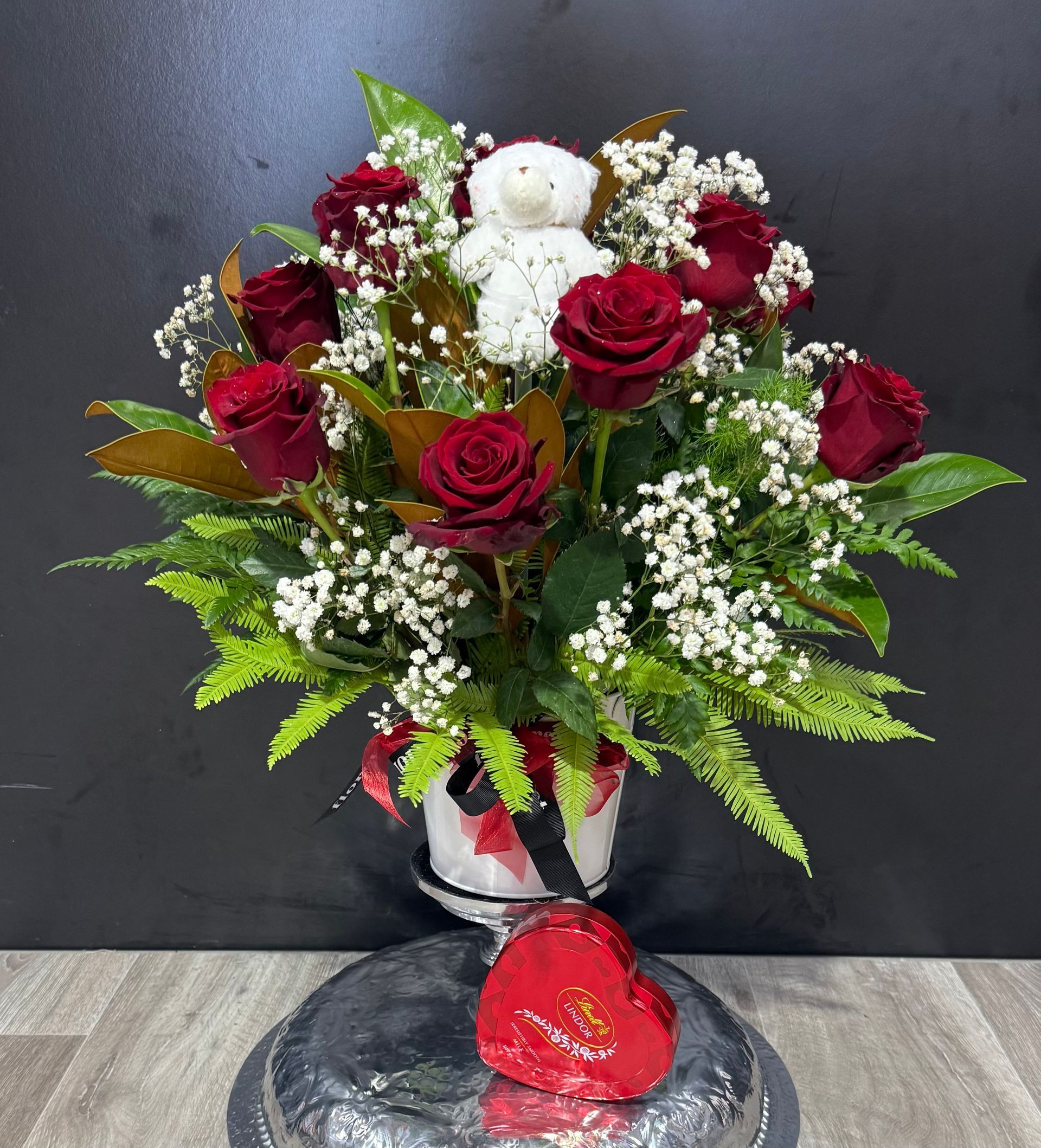 A Vase Filled With Red Roses and a Teddy Bear is Sitting on a Table — Floret In Lismore, NSW