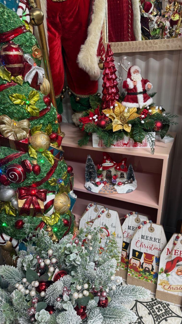 Christmas decorations on display: trees, Santa figurines, and festive ornaments in a shop setting.