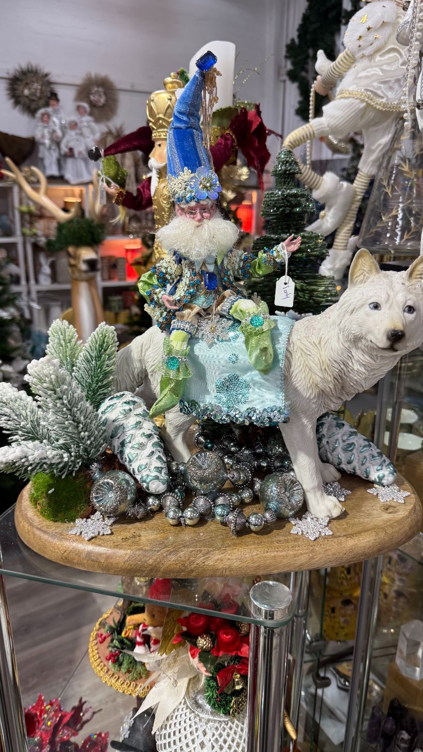 A whimsical gnome rides a white wolf; festive, holiday decor on display.