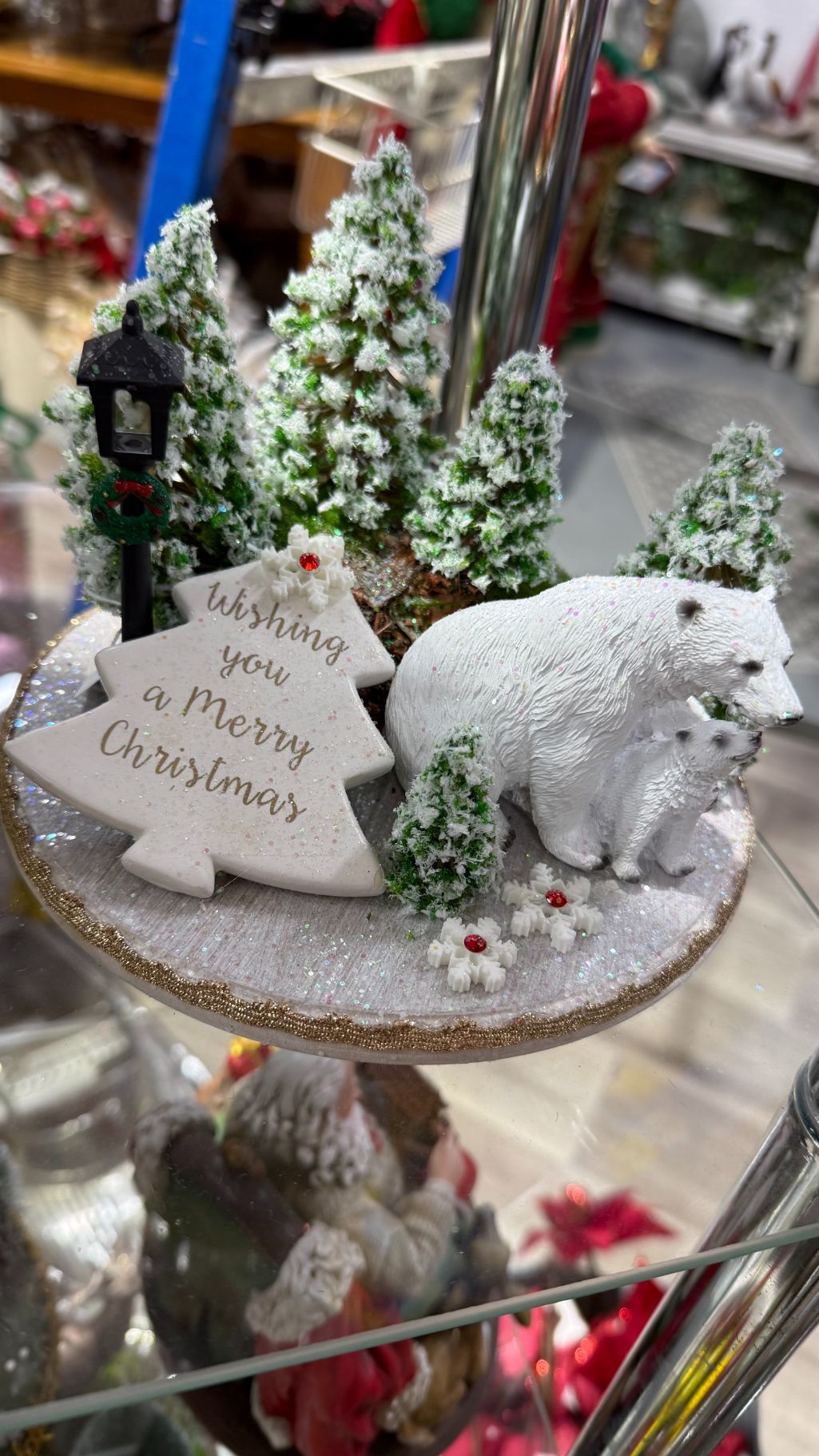 Christmas scene: polar bears with cubs near a snow-covered tree, a lamppost, and a sign wishing Merry Christmas.