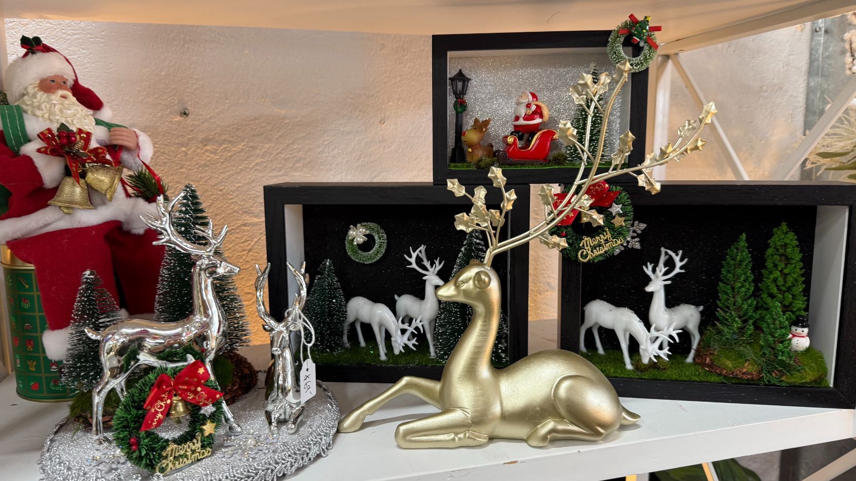 Christmas decorations: Santa, deer figurines, snow-covered scene with framed shadow boxes featuring reindeer and a sleigh.