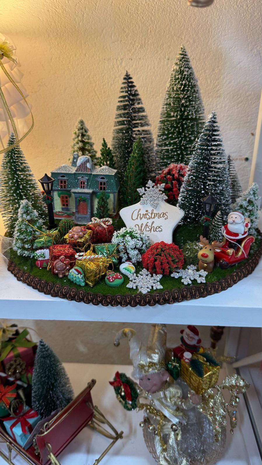 Christmas village scene with house, trees, and decorations; includes sign that says