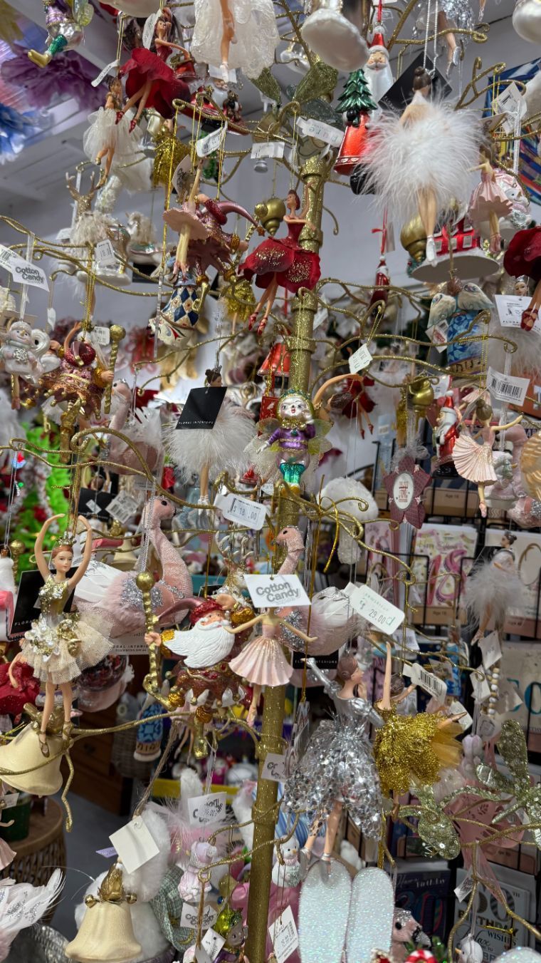 Ornament display stand featuring ballet-themed ornaments: ballerinas, tutus, feathers, red, pink, gold accents.