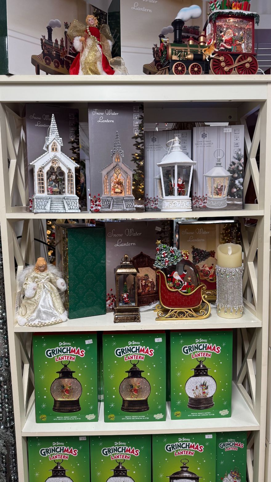 Shelves of Christmas decorations: snow globes, angel figures, lanterns, and a train.