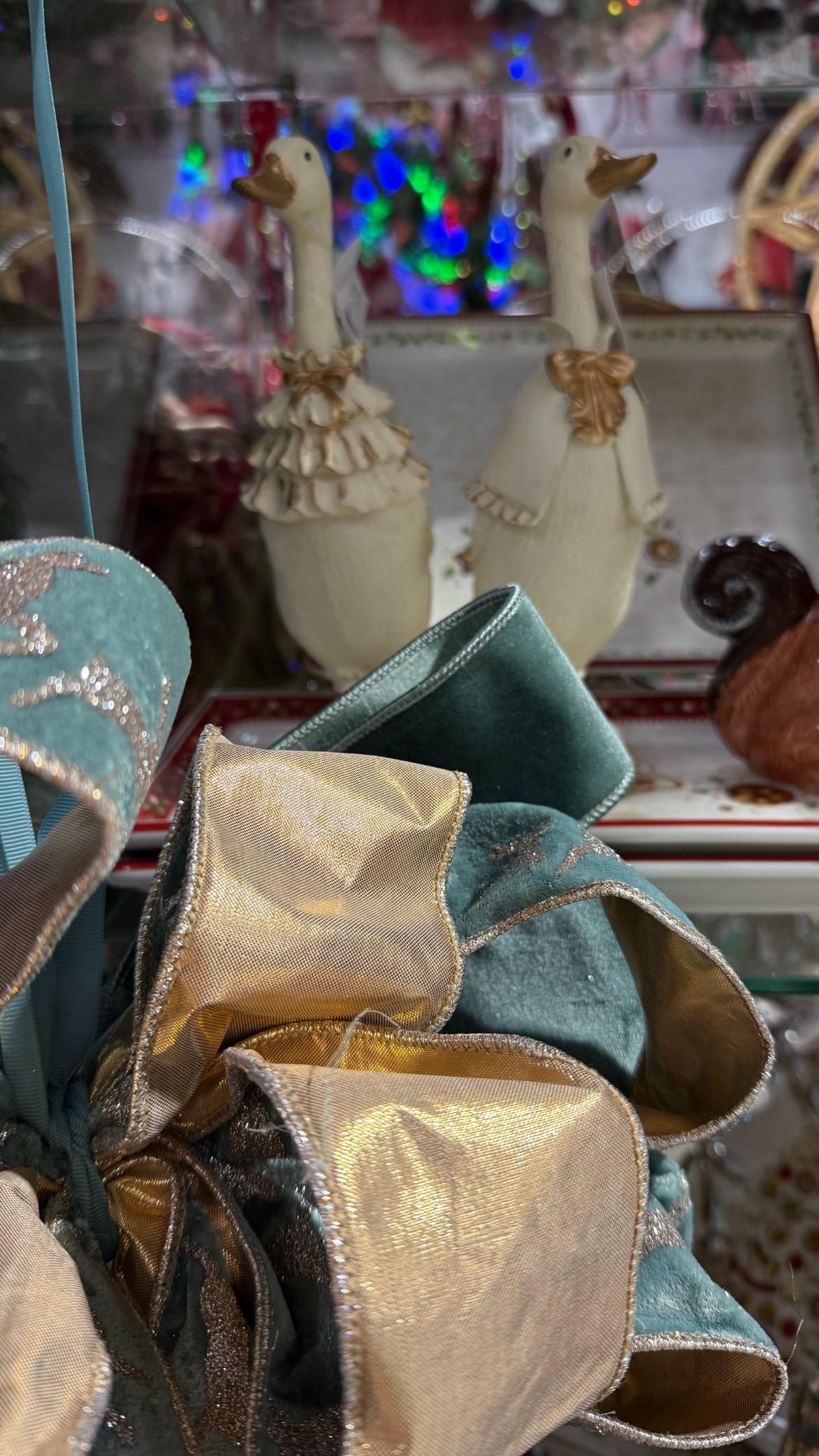Two decorative white geese with gold accents, teal and gold bow in the foreground. | Jingle Bell Christmas