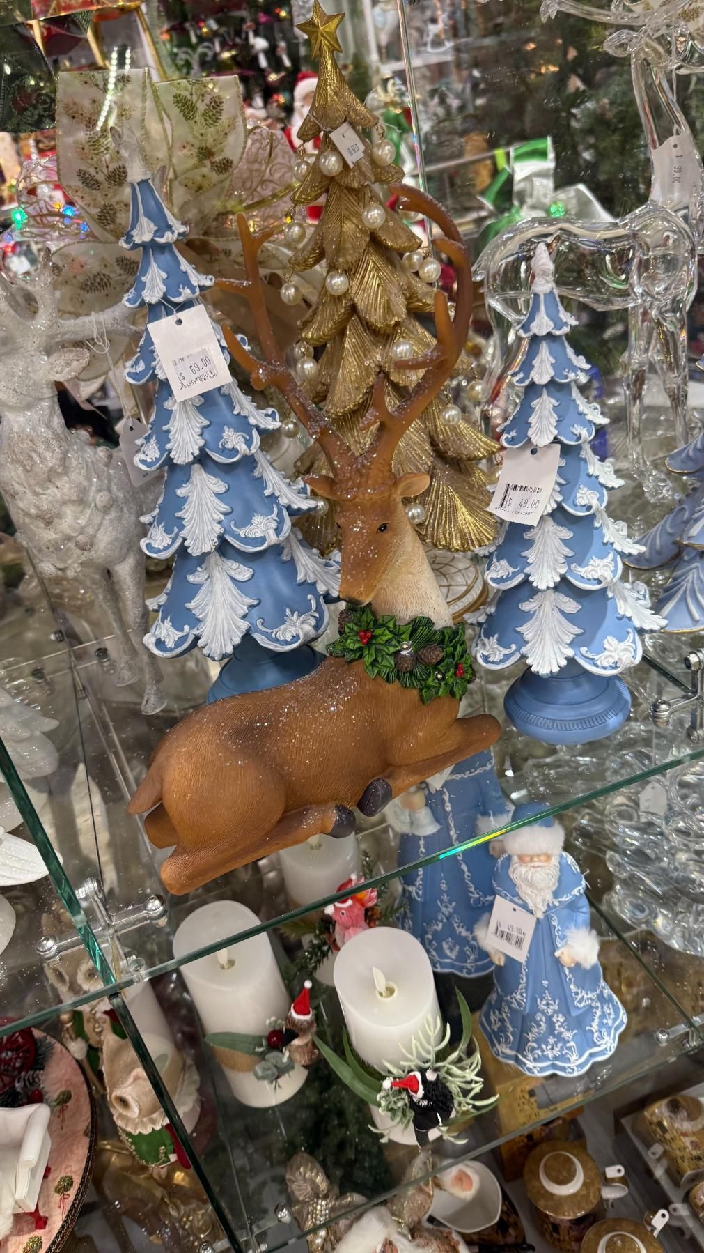 Christmas decorations on a shelf: reindeer, blue trees, gold accents, candles. | Jingle Bell Christmas