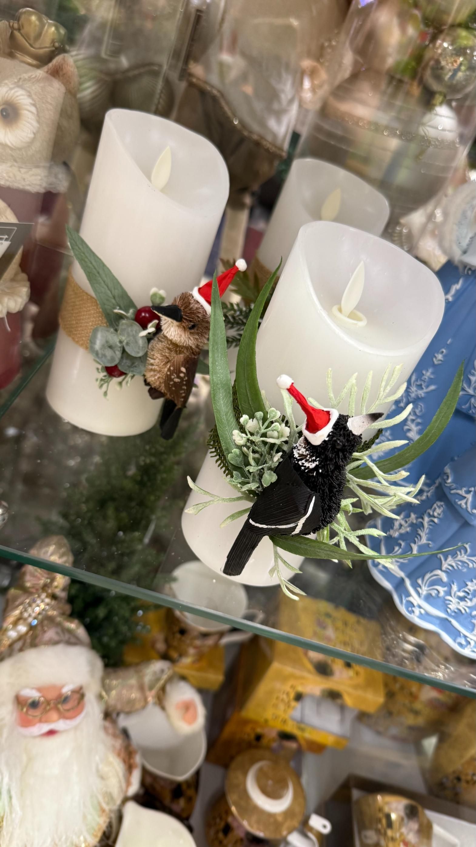 Two white pillar candles decorated with Christmas ornaments and greenery. | Jingle Bell Christmas