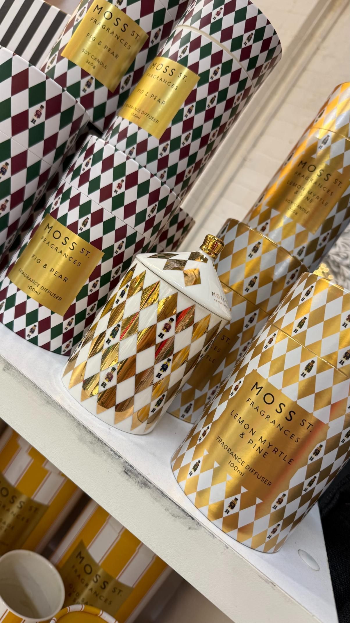 Various decorative cylindrical containers with gold accents and diamond patterns on a white shelf. | Jingle Bell Christmas