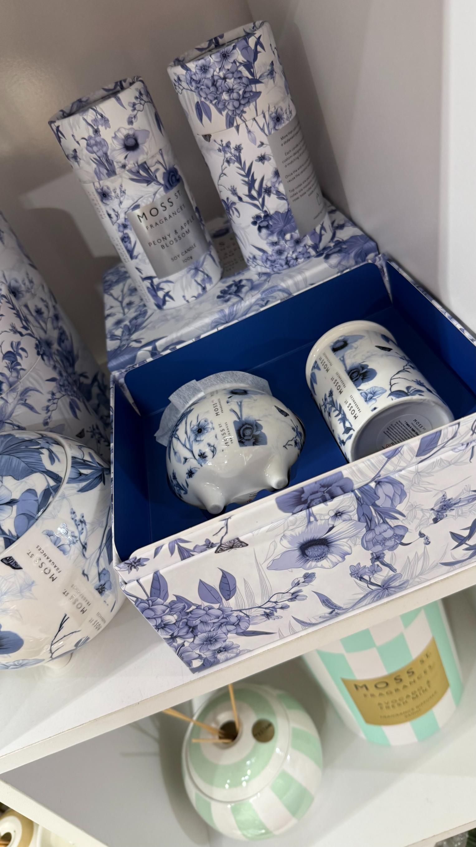 Gift set with blue floral-patterned ceramic items and two matching wrapped tubes in a box on a shelf | Jingle Bell Christmas