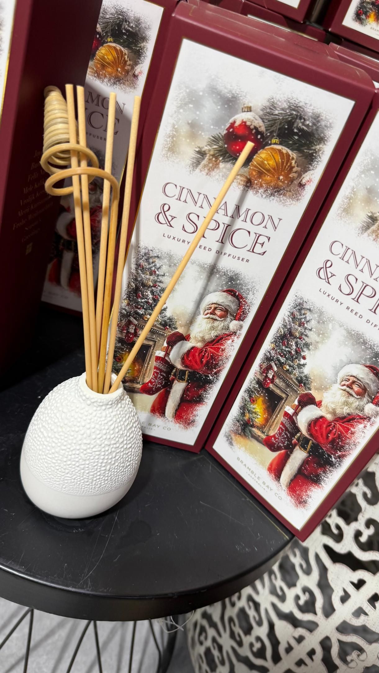 White ceramic diffuser with reeds, beside Christmas-themed boxes with Santa and forest scene | Jingle Bell Christmas