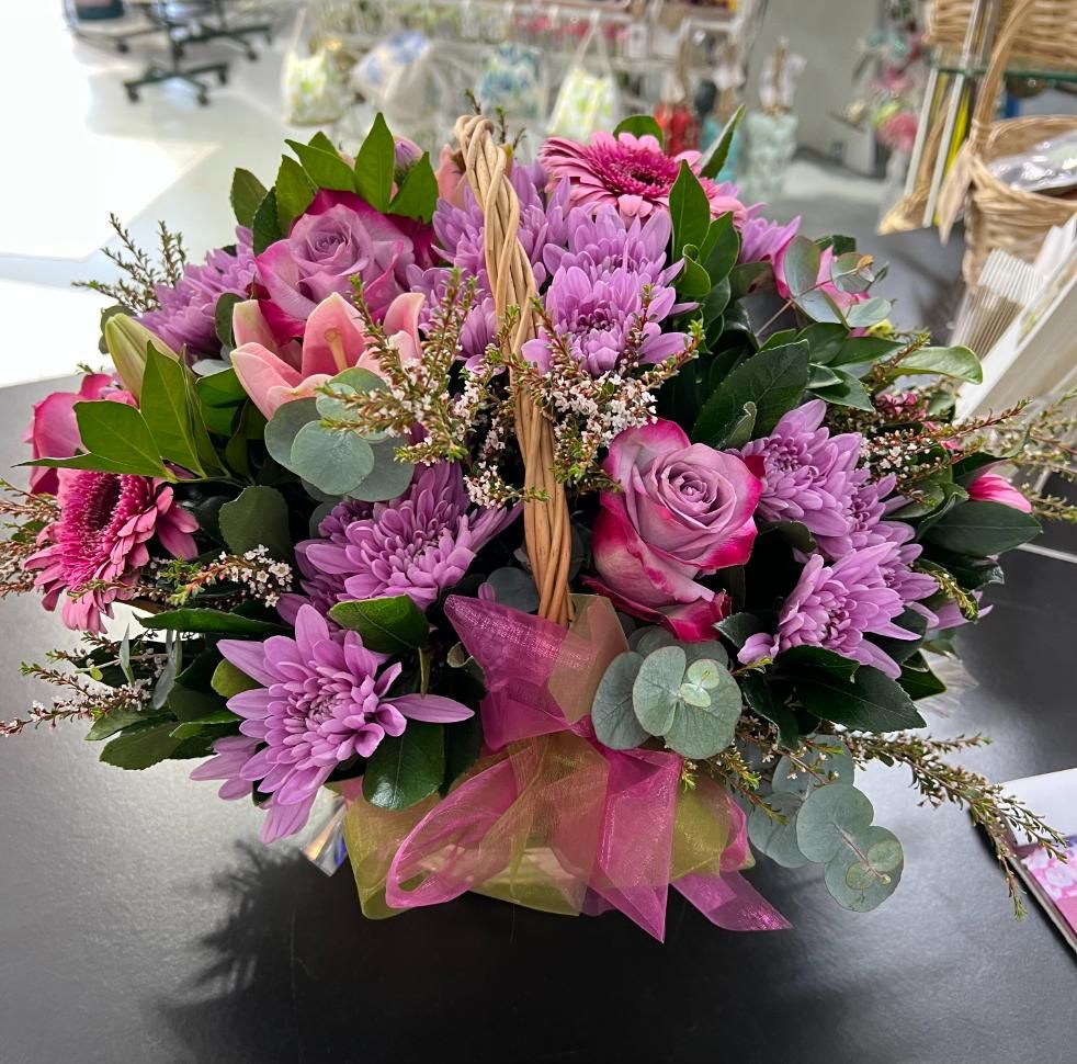 A Basket Filled With Purple and Pink Flowers is Sitting on a Table — Floret In Wollongbar, NSW