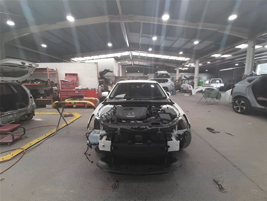 A White Car is Being Worked on in a Garage — Vanderpoel Smash Repairs in Tuggerah, NSW