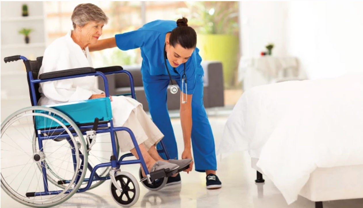 elderly woman in wheel chair getting assistance from female nurse