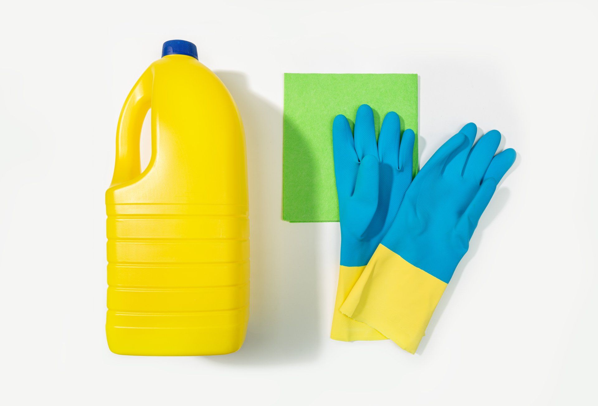 Close up of bleach bottle, protective gloves and rag.