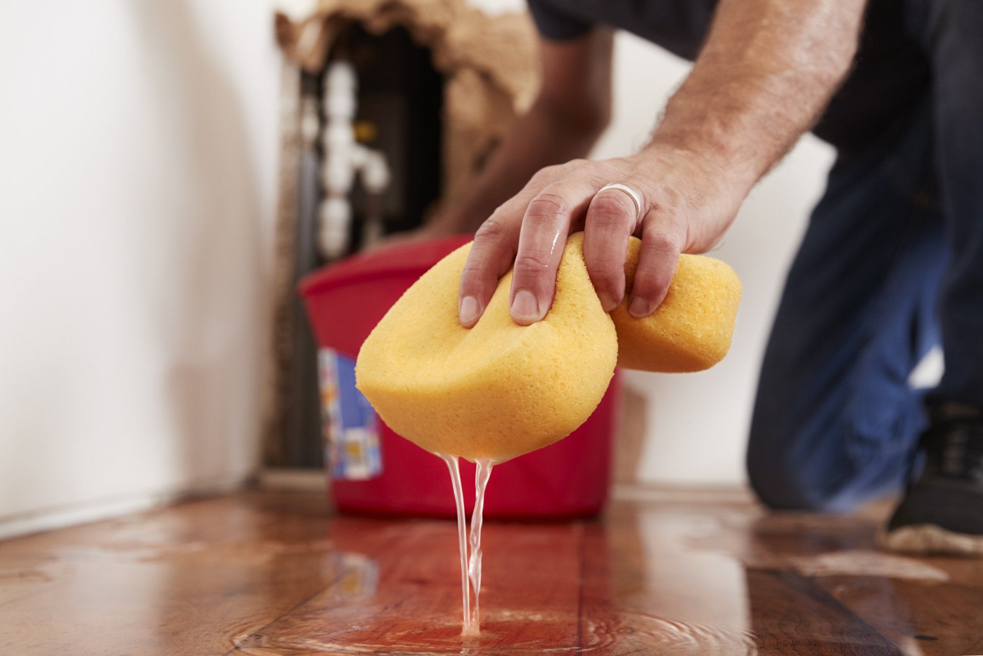 Man removing water from flooded floor with a sponge.