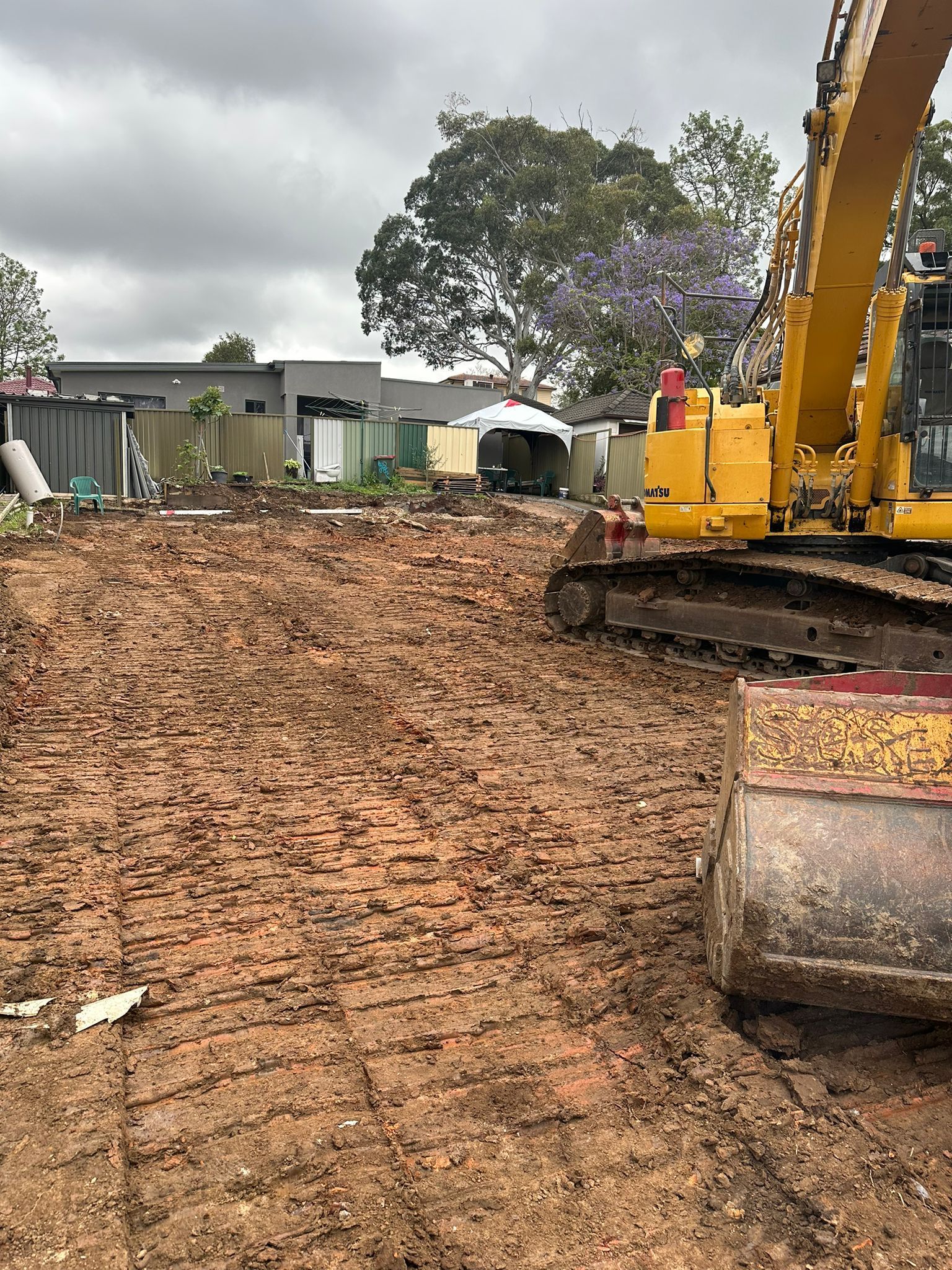 A yellow excavator is sitting in the middle of a dirt field.