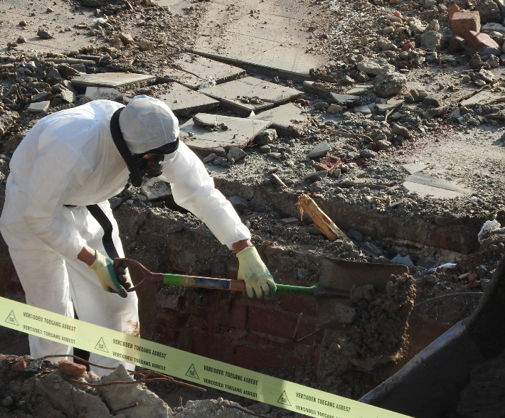 A man in a white suit is working on a brick wall
