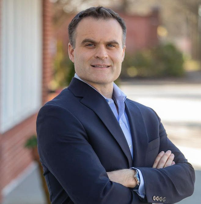 A man in a suit is standing with his arms crossed
