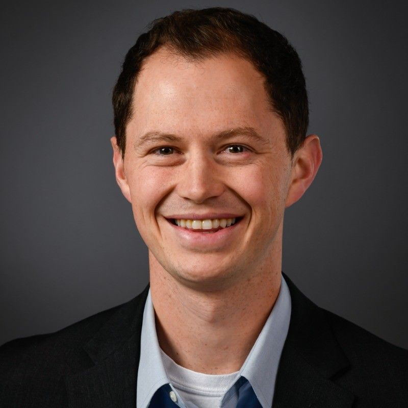 A man in a suit and tie is smiling for the camera.
