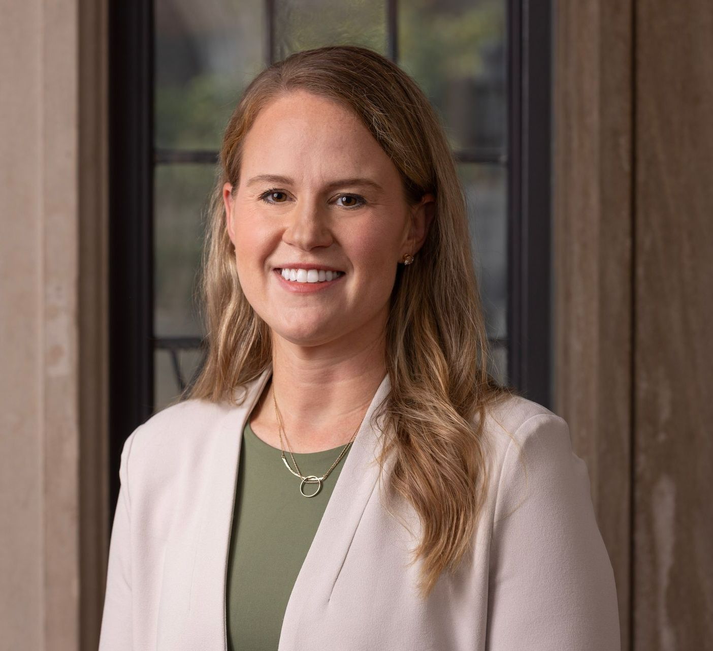A woman in a white jacket and green shirt is smiling for the camera.