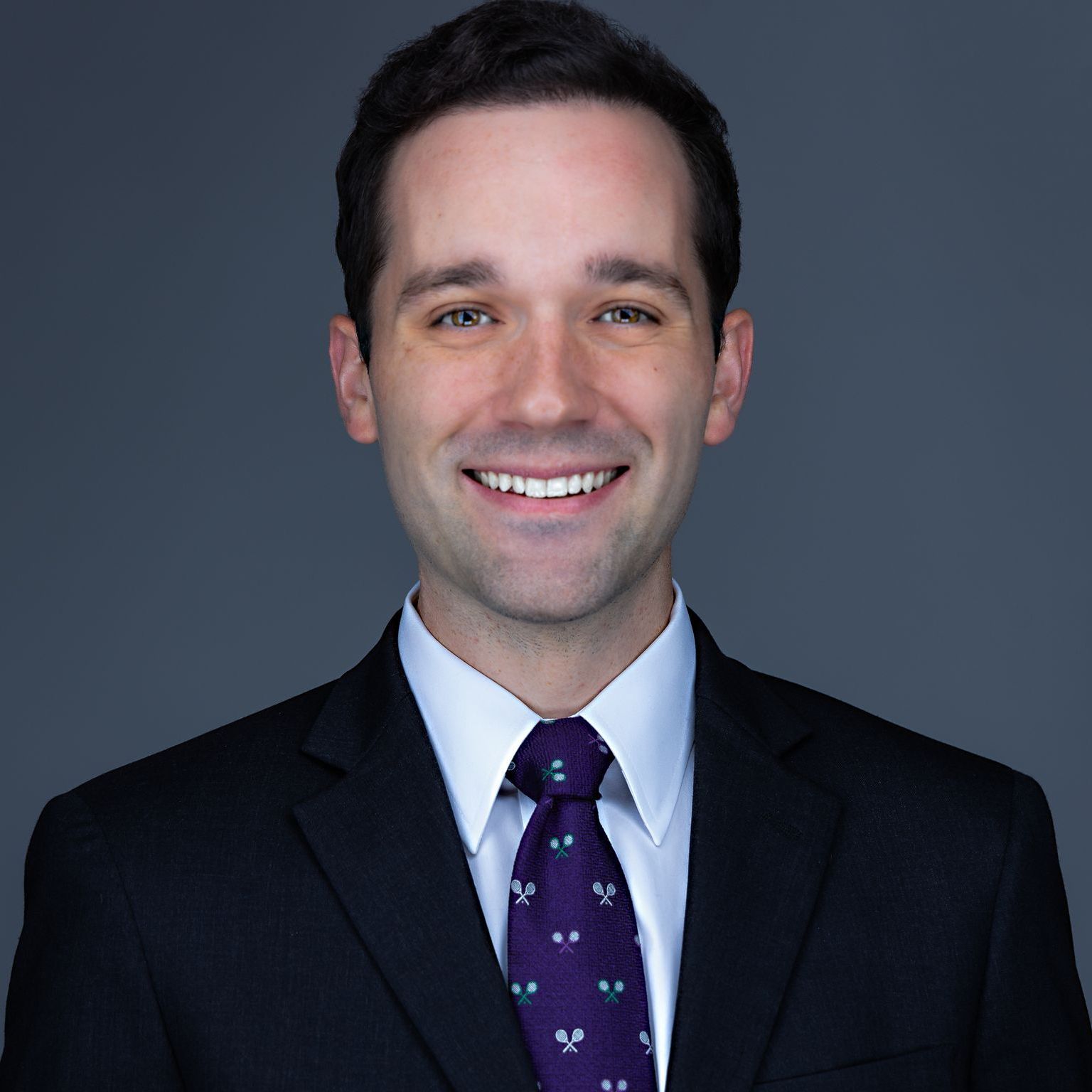 A man in a suit and tie is smiling for the camera