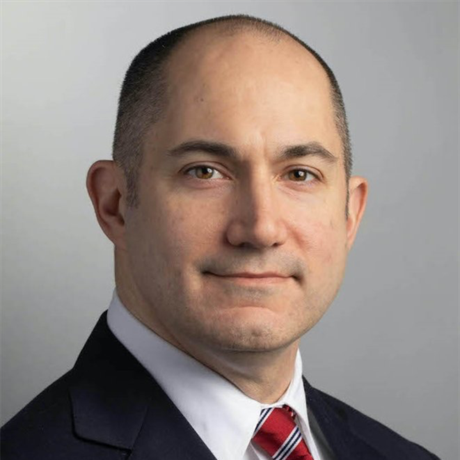 A man in a suit and tie is smiling for the camera