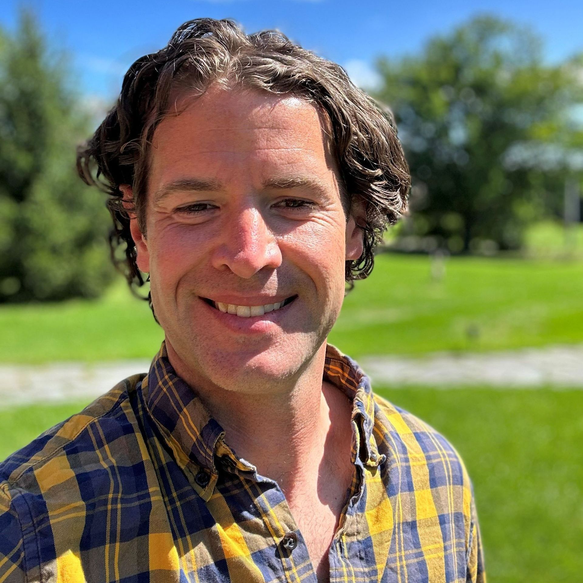 A man in a plaid shirt is smiling for the camera
