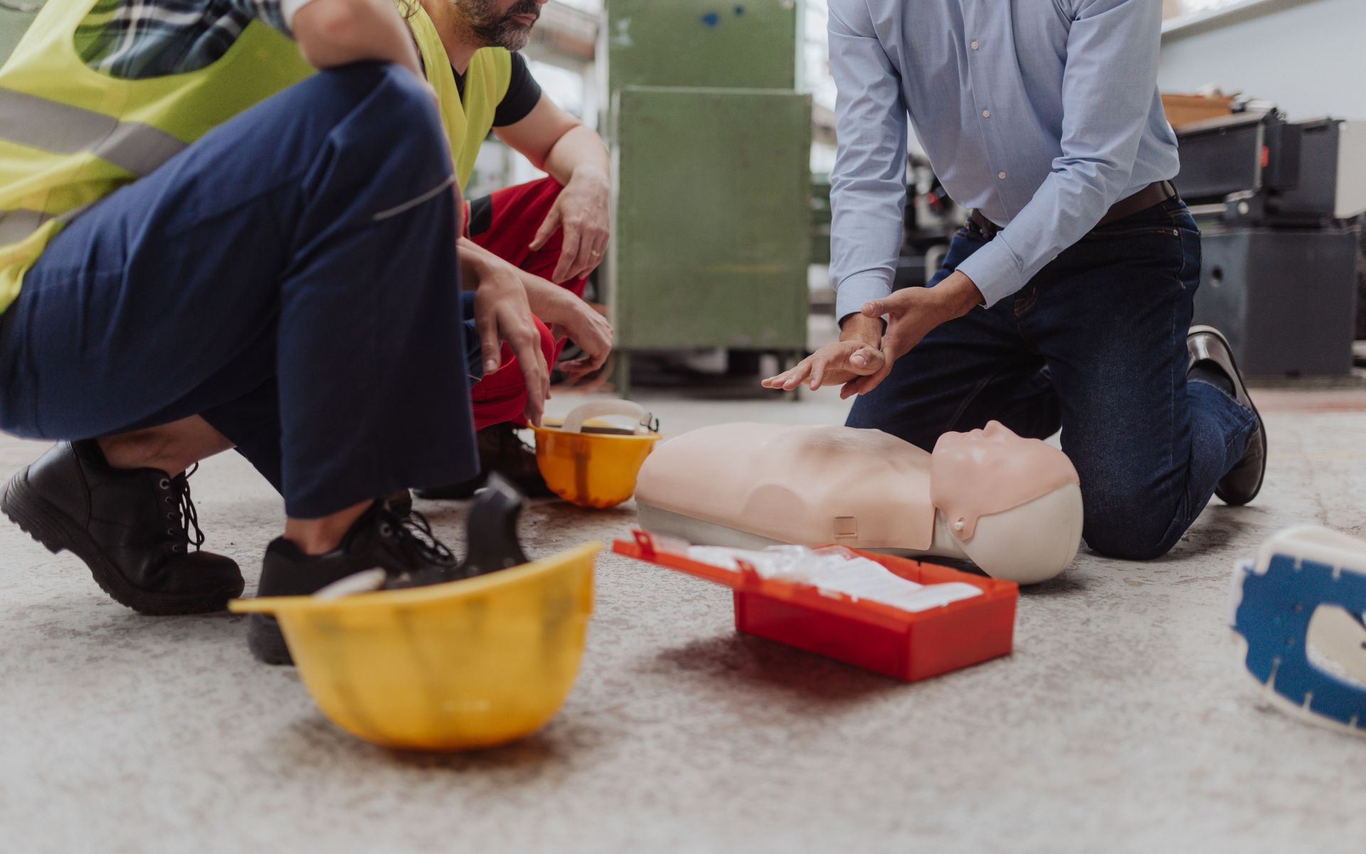An instructor showing first medical aid on a doll during a training course indoors. An instructor showing first medical aid on a doll during a training course indoors.