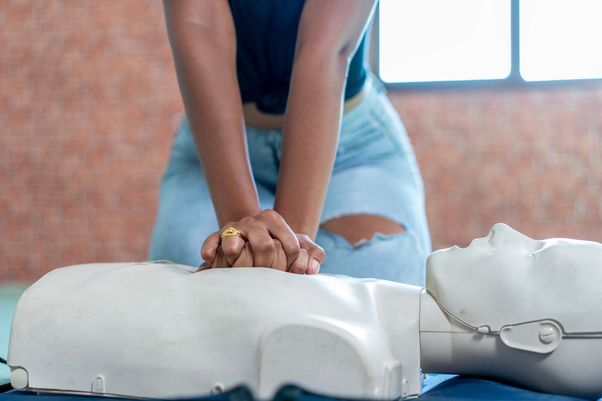 Hands performing CPR on a training mannequin during a first aid training course.