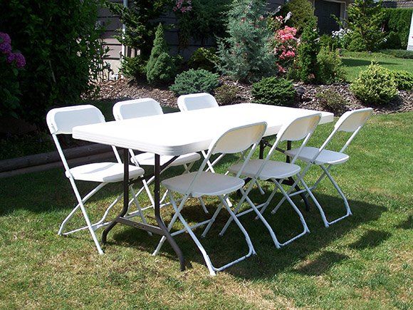 A table and chairs are sitting on a lush green lawn.
