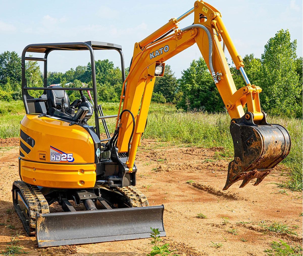A yellow excavator is sitting in the middle of a dirt field.