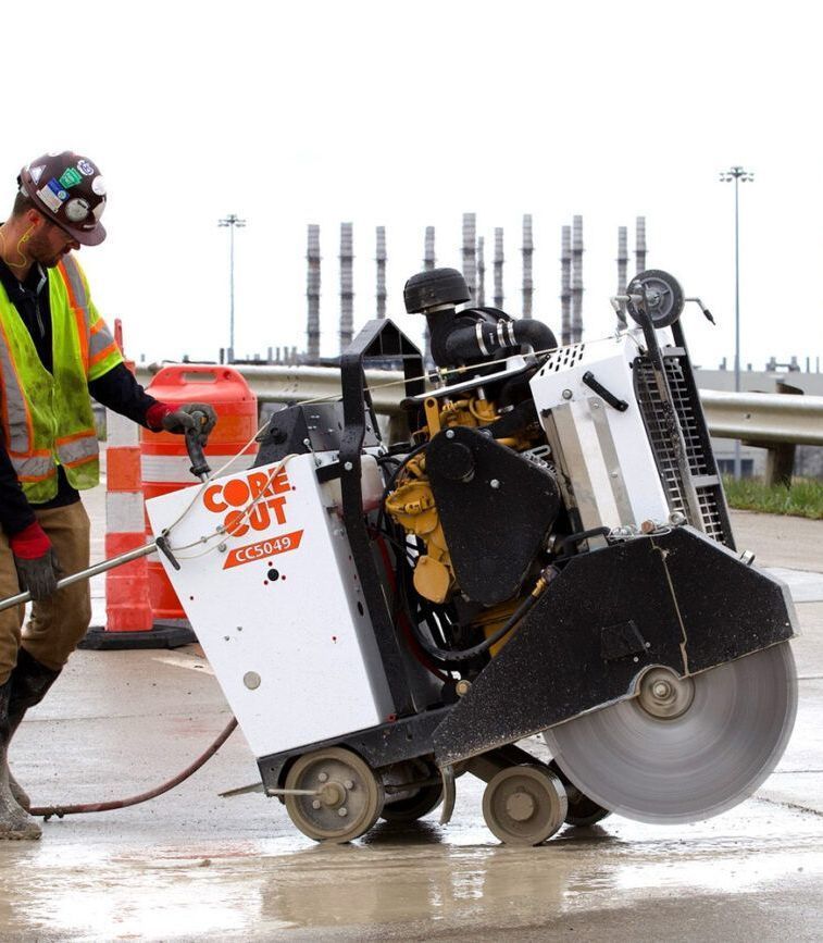 A man is using a cork cut machine to cut concrete