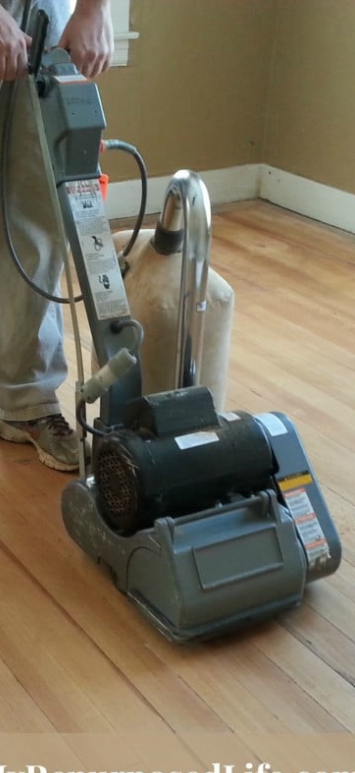 A man is sanding a wooden floor with a machine.