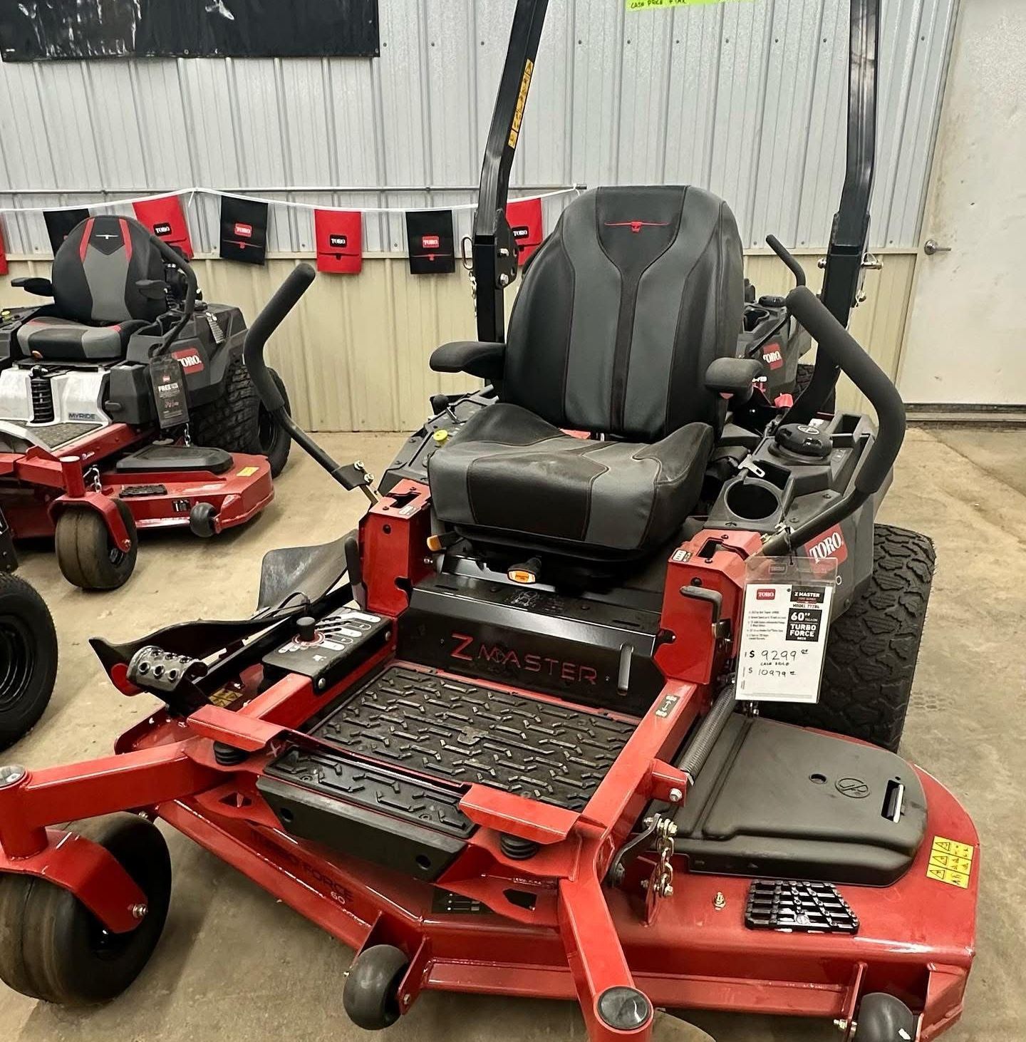 A red and black lawn mower is parked in a garage.
