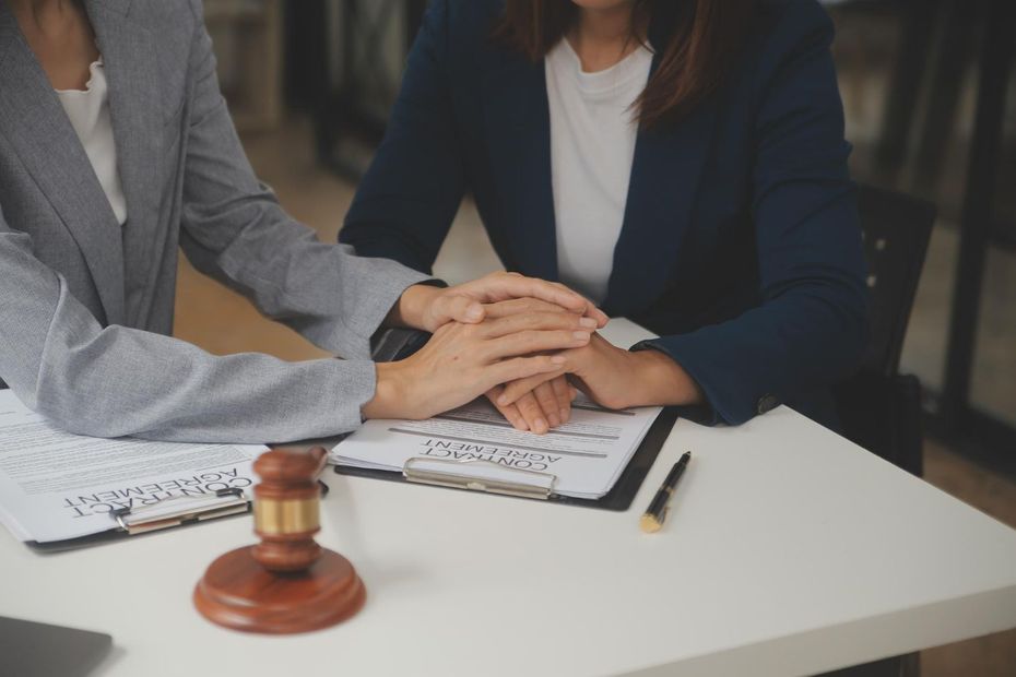 Two people signing legal documents with a judge’s gavel on a table