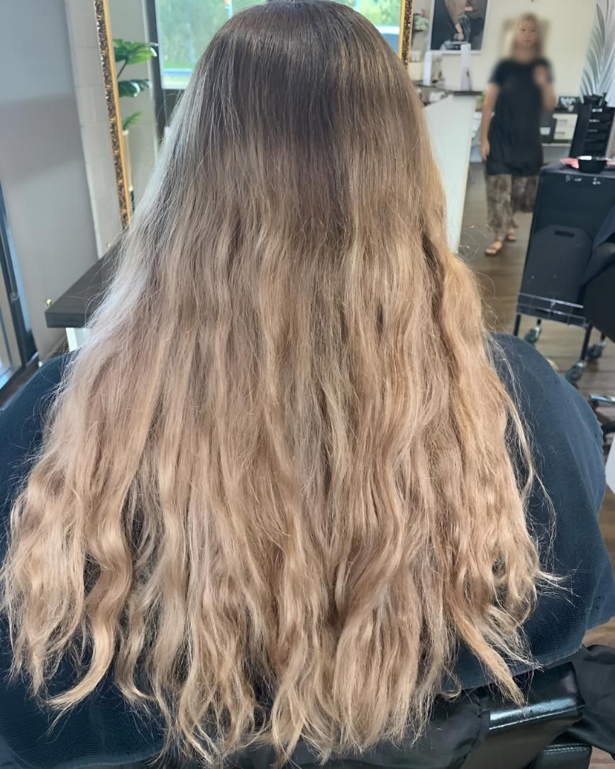 A Woman With Long Blonde Hair Is Sitting — Beautique Hair Lounge & Beauty Bar In Condon, QLD